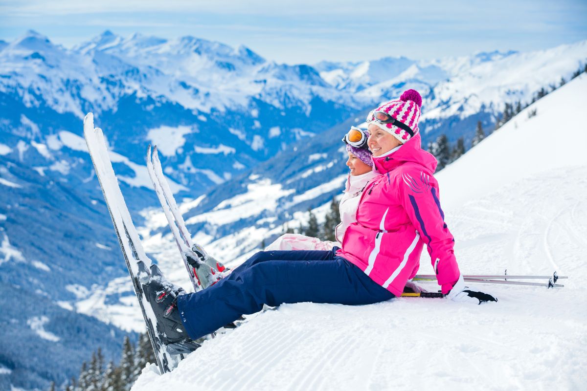 A mother and daughter seating in the slope ski resort.